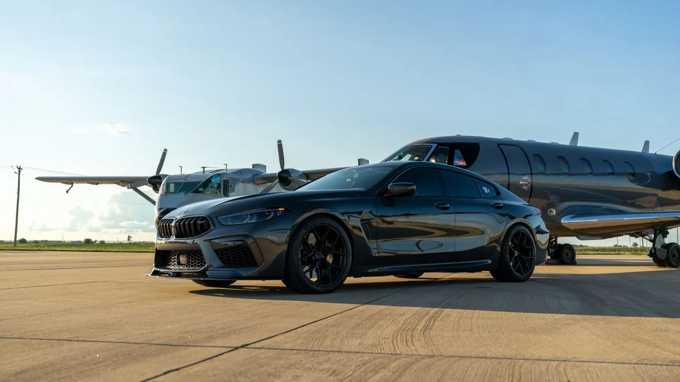 A luxury car beside a private jet on an airport tarmac